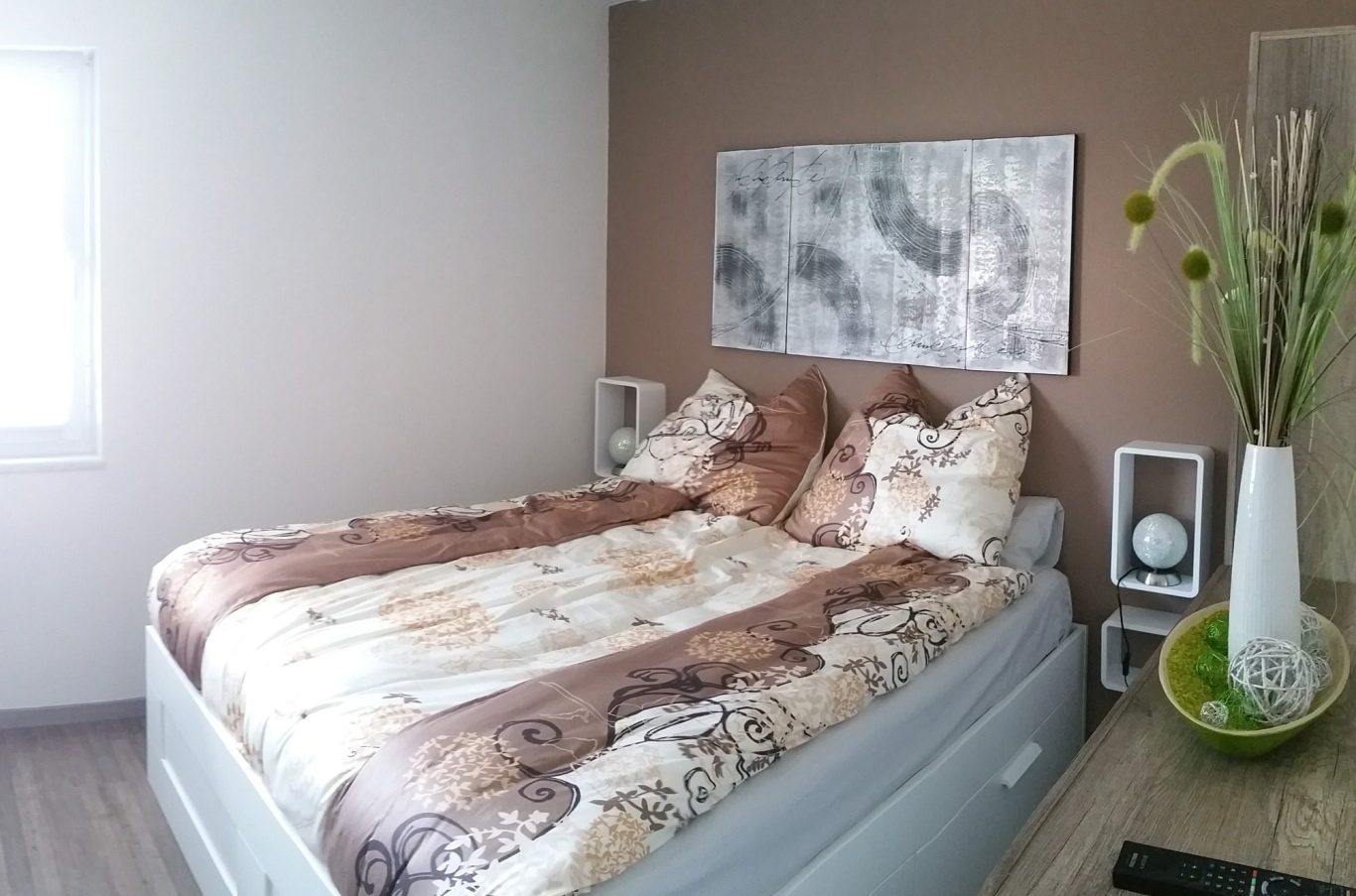 Schlafzimmer Doppelbett mit Bettwäsche erdifarbend mit modernen Bild über Bett